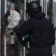 Police using a powersaw to get into a container believed to be connected to an organised crime gang