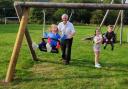 Councillor Steve Kay with (left to right) grandchildren Emily, Penelope and Thomas on the playing field at Charltons after swings were refurbished