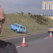 The local councillor rolls his eyes as a three car pile-up happens moments after telling a news team how safe the road was (Image: ITN Archive).