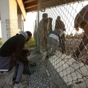Migrants climb through a fence on to the tracks near the Eurotunnel site at Coquelles in Calais, France