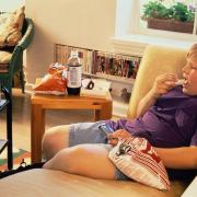 Overweight boy / child sitting on sofa watching television...
