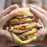 Talking junk: A person eating a very large hamburger as unhealthy Western ways of living are likely to fuel a massive surge in cancer rates around the world, experts have claimed