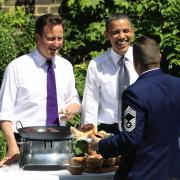 Prime Minister David Cameron (left) and US President Barack Obama serving food to a member of the military during a barbecue in the garden of 10 Downing Street, London. Picture: Matt Dunham/PA Wire