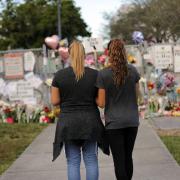 Sara Smith, left, and her daughter Karina Smith visit a makeshift memorial outside the Marjory Stoneman Douglas High School, where 17 students and faculty were killed in a mass shooting. Picture: AP