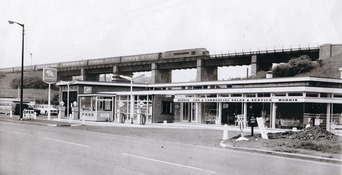 With a train flying behind, this Ansa garage and Morris showroom was built on the site of the Victoria Buildings at Langley Moor in 1965