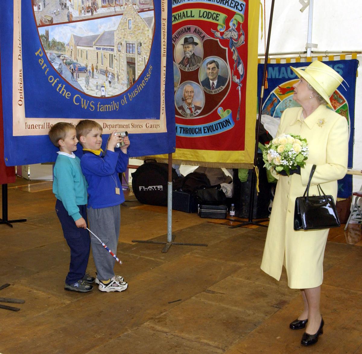 The Queen, Elizabeth II, is filmed by two young admirers while looking at Trade Union banners at Easington, County Durham on the second day of her visit to the region during her Golden Jubilee tour of the nation