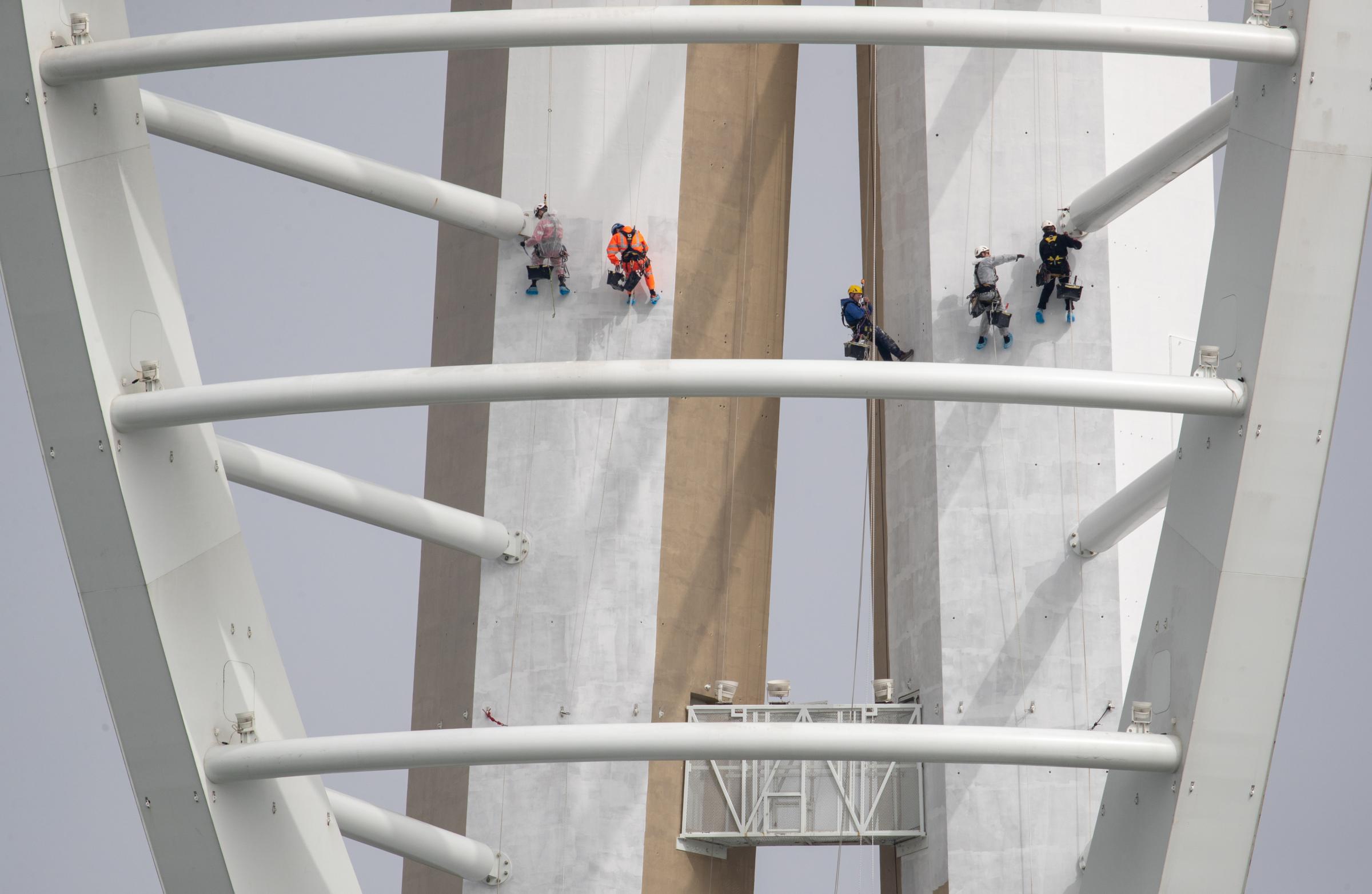 Contractors paint the outside of the Spinnaker Tower in Portsmouth harbour, which is being repainted its original white after the branding arrangement with Emirates ended on June 30, 2020 Picture: ANDREW MATTHEWS/PA