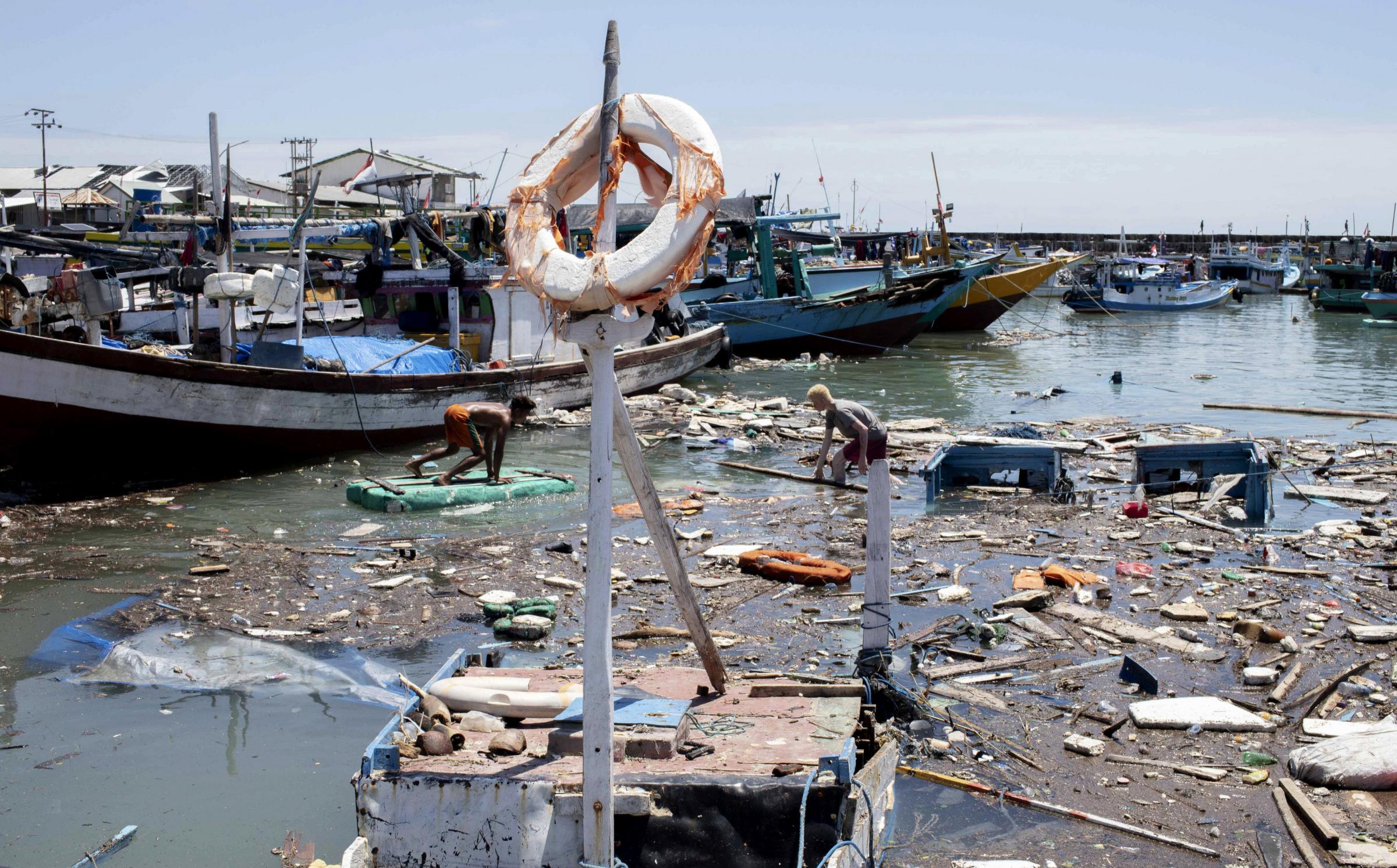 Indonesian men look for salvageable items amid debris and damaged boats following a storm at a port in Kupang, East Nusa Tenggara province, Indonesia Picture: ARMIN SEPTIEXAN/AP.