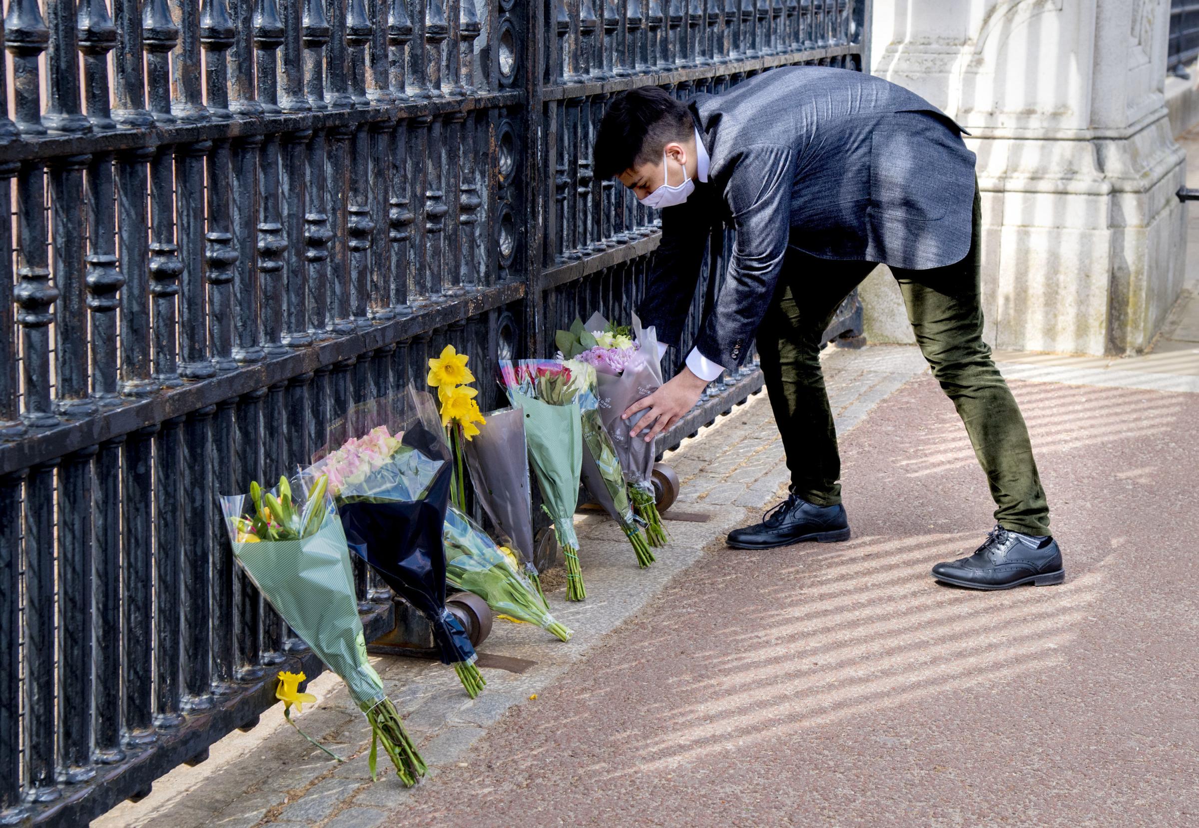 A member of the public leaves flowers outside Buckingham Palace, London, following the announcement of the death of the Duke of Edinburgh at the age of 99. Picture date: Friday April 9, 2021. PA Photo. Prince Philip, 99, was the longest-serving consort