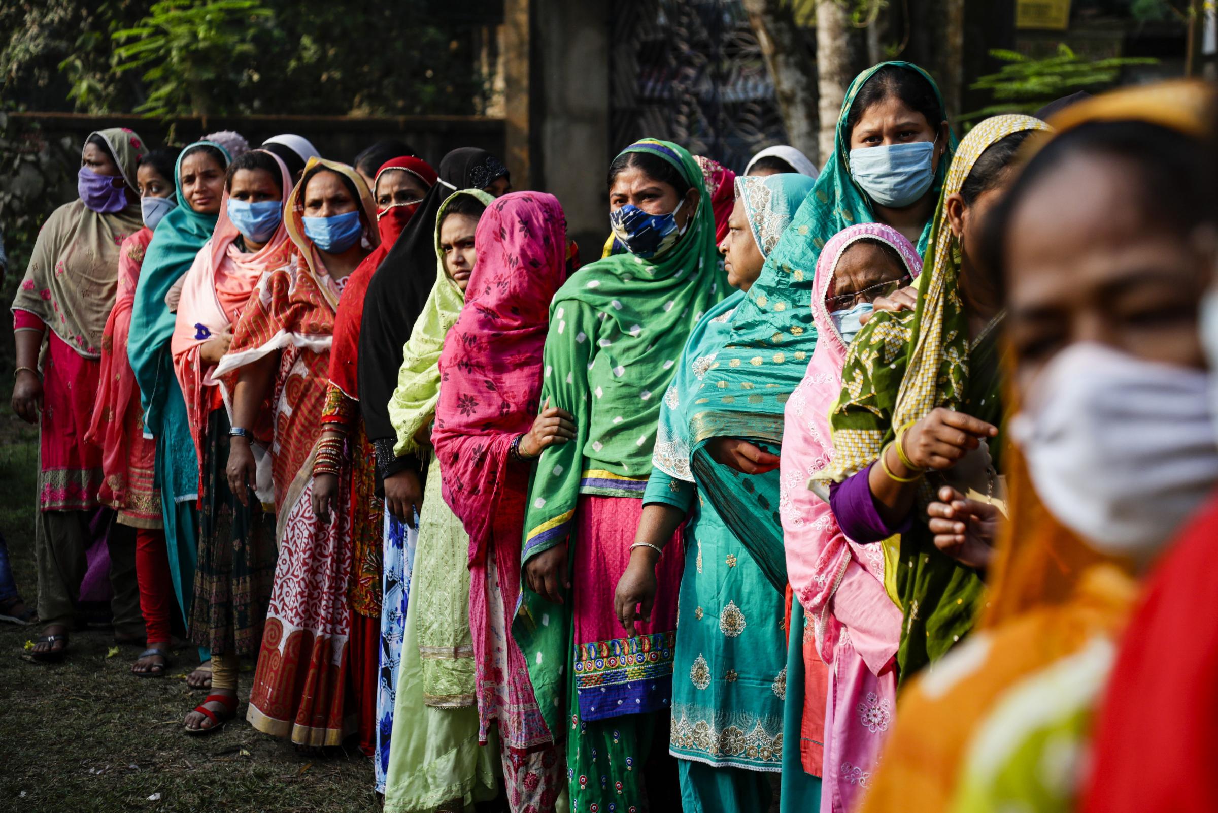Voters wearing masks as a precaution against the coronavirus stand in queue to cast their votes at a polling booth during third phase of West Bengal state elections in Baruipur, South 24 Pargana district, India Picture: BIKAS DAS/AP.