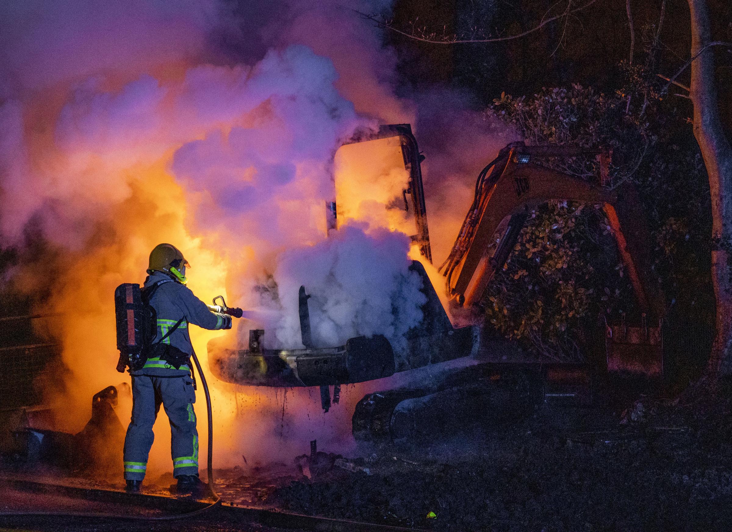 A member of the Northern Ireland Fire and Rescue Service (NIFRS) extinguishes a JCB digger which has been set alight close to the Loyalist Nelson Drive Estate in the Waterside of Derry City, Co. Londonderry Picture: LIAM MCBURNEY/PA.