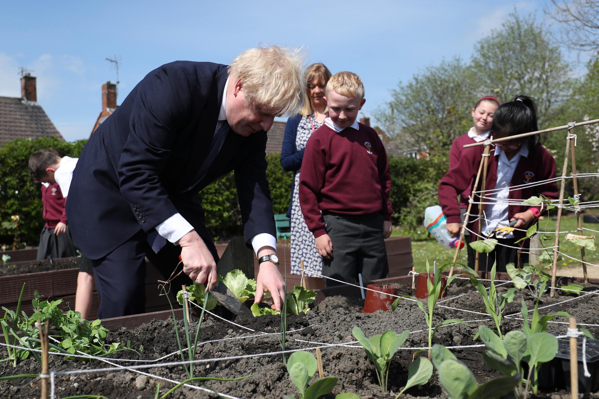 Prime Minister Boris Johnson helps out in the vegetable garden during a visit to Cleves Cross Primary school in Ferryhill, County Durham. Picture date: Thursday May 13, 2021.
