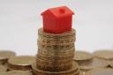 Plastic model of a house sitting on a pile of one pound coins, as stamp duty should be scrapped for people downsizing their home to raise money for their retirement, according to an insurer.