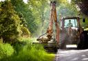mowing grass verge with tractor .mowing grass shoulder along road with tractor mower in public space.