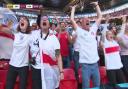 Nina Farooqi, centre draped in a flag and camera, caught celebrating England's first goal at Wembley. Pic: BBC