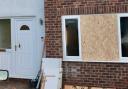A boarded-up window and damaged door at the property