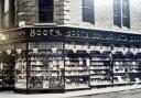 FIRST GLANCE: The original Boots shop front with Victoria Avenue going off to the right and Newgate Street to the left. A poster in the window advertises “Pure Drugs” – a Victorian Boots tradename. Above the window on the left are two enamel signs.