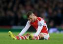 INJURY: Arsenal's Jack Wilshere sits injured on on the pitch. The midfielder will be out for approximately three months after undergoing successful surgery on his left ankle, Arsenal have announced