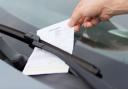 A Generic Photo of a parking ticket being placed on a car windscreen.