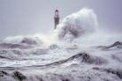 Huge waves crash the against the sea wall and Roker Lighthouse in Sunderland in the tail end of Storm Arwen