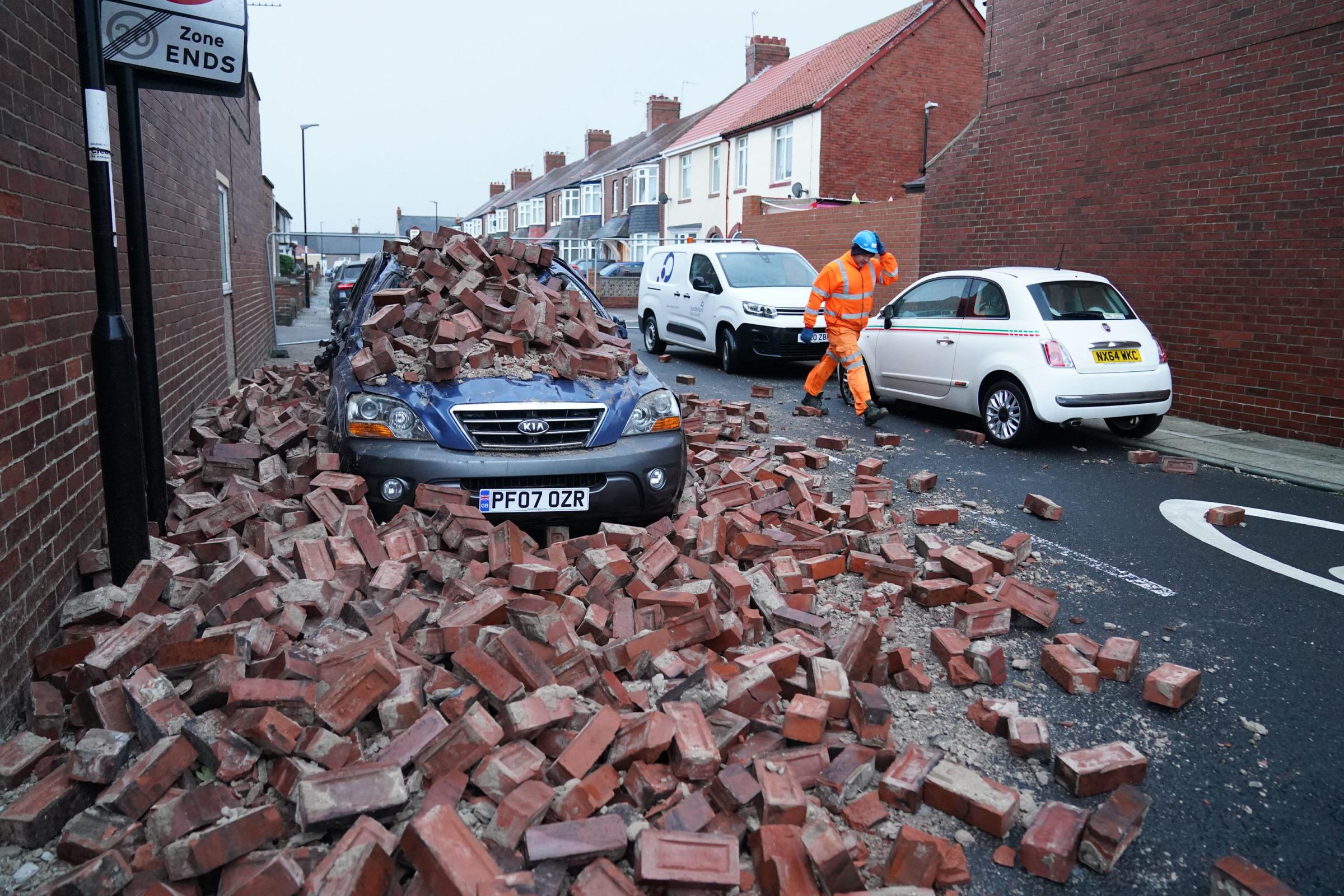 A man makes safe fallen masonry from a property, which has damaged a nearby car, on Gloucester Avenue in Roker, Sunderland, after gusts of almost 100 miles per hour battered some areas of the UK during Storm Arwen. Picture date: Saturday November 27,