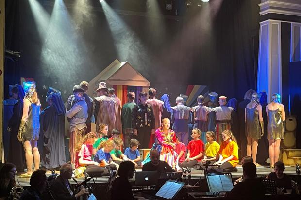 Joseph, played by Scott Edwards, with the narrator in black, Karen Davison, surrounded by the cast of Joseph at the Witham Hall, Barnard Castle