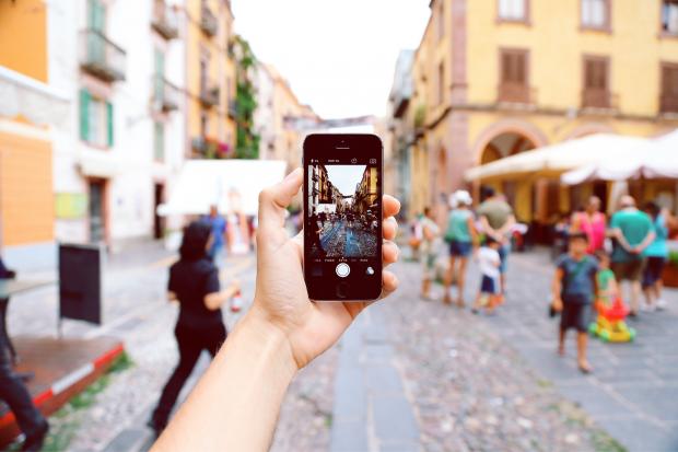 The Northern Echo: A tourist taking a picture of a busy street on their phone. Credit: Canva