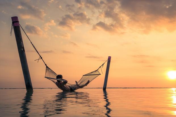 The Northern Echo: A man relaxing over the water in a hammock. Credit: Canva