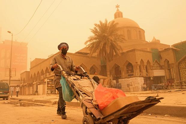 A man pushes a cart during a sandstorm in Baghdad, Iraq Picture: HADI MIZBAN/AP