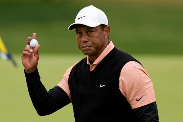 Tiger Woods holds a golf ball aloft