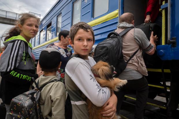 A boy holds his pet dog as his family evacuated from the war-hit area gets on an evacuation train in Pokrovsk, eastern Ukraine, Saturday, June 25, 2022