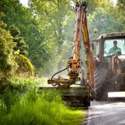 mowing grass verge with tractor .mowing grass shoulder along road with tractor mower in public space.
