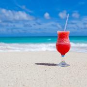 A cocktail sitting on a beach in the sun. Credit: Canva