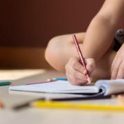 Photo via Canva shows a child alone drawing.