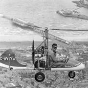 DARING YOUNG MAN: Ernie Brooks, complete with wig, takes his gyrocopter for a spin over Brighton pier.