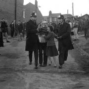 A woman pleads for mercy as her husband is led away by police