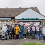 Dozens of patients with placards reading “Save Our Surgery” gathered outside the practice on