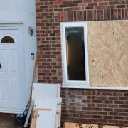 A boarded-up window and damaged door at the property
