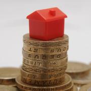 Plastic model of a house sitting on a pile of one pound coins, as stamp duty should be scrapped for people downsizing their home to raise money for their retirement, according to an insurer.