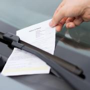 A Generic Photo of a parking ticket being placed on a car windscreen.