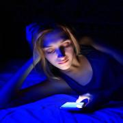A young girl in the dark on her smartphone.