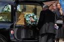 A funeral director places a floral tribute and photograph behind the coffin of Daniel Anjorin (Jonathan Brady/PA)